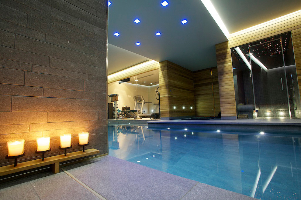 Photo of a mid-sized modern indoor l-shaped lap pool in London with natural stone pavers.