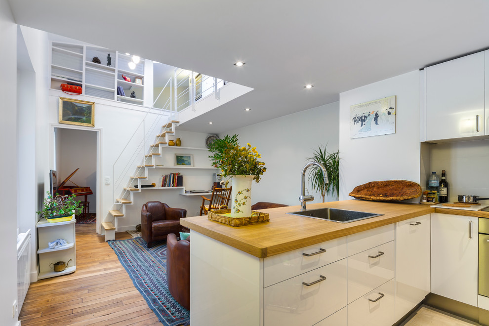 Mid-sized contemporary l-shaped open plan kitchen in Paris with wood benchtops, medium hardwood floors and a peninsula.