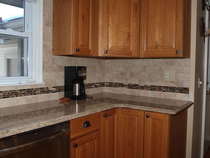 Mid-sized transitional l-shaped eat-in kitchen photo with raised-panel cabinets, medium tone wood cabinets, quartz countertops, multicolored backsplash, glass tile backsplash, stainless steel appliances and no island