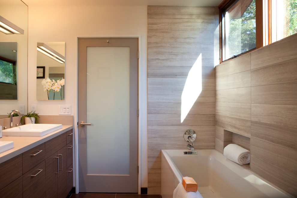 This is an example of a mid-sized contemporary master bathroom in San Francisco with a vessel sink, an alcove tub, flat-panel cabinets, dark wood cabinets, a curbless shower, a two-piece toilet, gray tile, limestone, brown walls, porcelain floors, engineered quartz benchtops, brown floor and a hinged shower door.