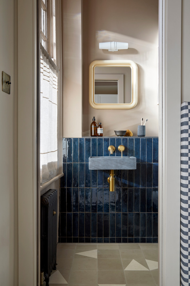 Small modern master bathroom in London with an open shower, a wall-mount toilet, blue tile, ceramic tile, pink walls, cement tiles, a wall-mount sink, beige floor, an open shower and a single vanity.