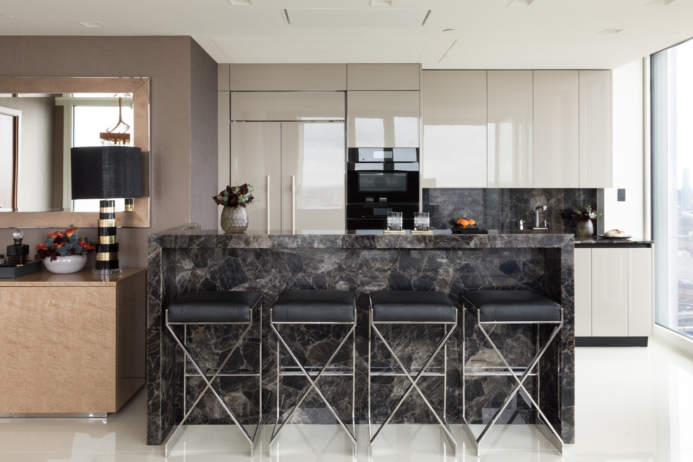Photo of a small contemporary galley open plan kitchen in London with flat-panel cabinets, black splashback, stone slab splashback, with island, white floor, black benchtop, an integrated sink, grey cabinets, black appliances and porcelain floors.