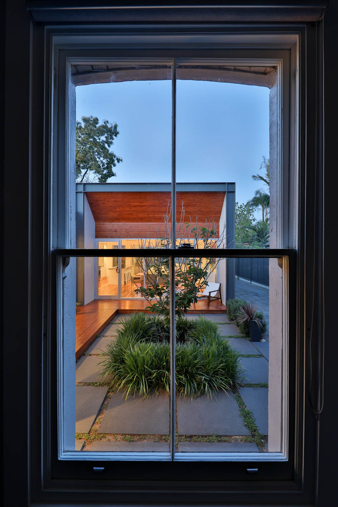 Cette image montre une terrasse design de taille moyenne avec une cour et des pavés en béton.