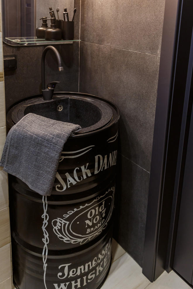 Свежая идея для дизайна: туалет с инсталляцией, черной плиткой, керамогранитной плиткой, черными стенами, полом из керамогранита, монолитной раковиной и бежевым полом - отличное фото интерьера