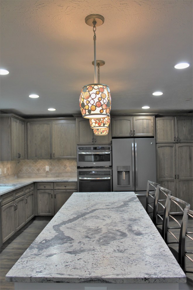 Eat-in kitchen - large transitional u-shaped laminate floor and brown floor eat-in kitchen idea in Indianapolis with a farmhouse sink, flat-panel cabinets, medium tone wood cabinets, granite countertops, beige backsplash, mosaic tile backsplash and an island