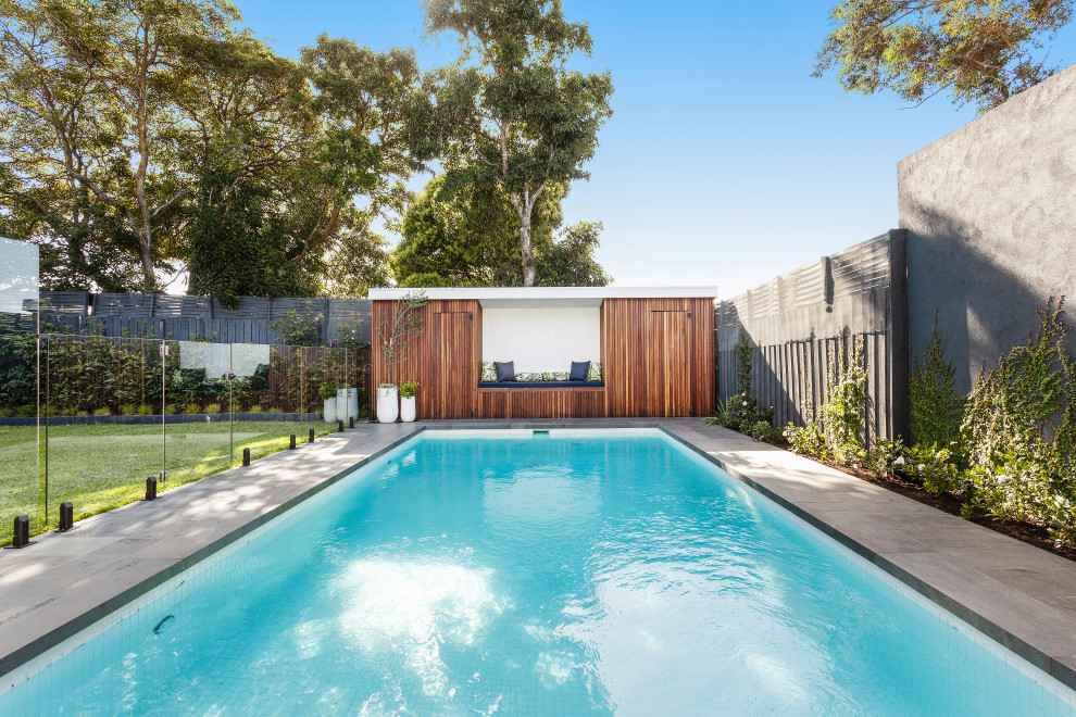 Photo of a large contemporary backyard rectangular pool in Melbourne with a pool house and natural stone pavers.