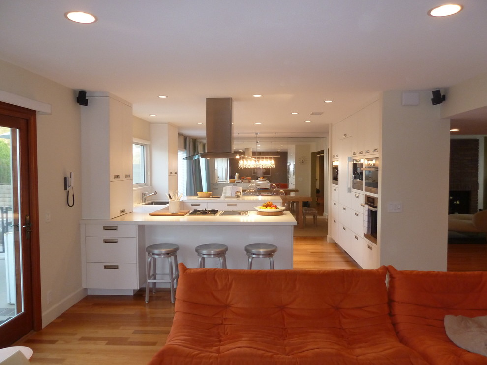 Eat-in kitchen - mid-sized contemporary u-shaped medium tone wood floor eat-in kitchen idea in Los Angeles with an undermount sink, flat-panel cabinets, white cabinets, quartz countertops, stainless steel appliances and a peninsula
