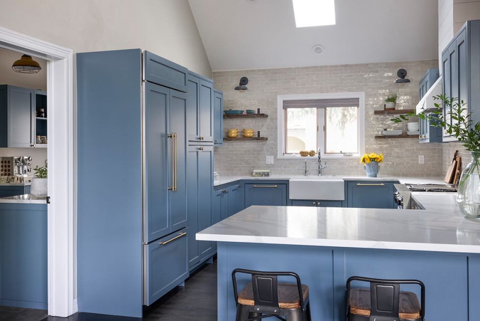 Inspiration for a mid-sized country u-shaped kitchen in Denver with a farmhouse sink, shaker cabinets, blue cabinets, quartz benchtops, white splashback, subway tile splashback, panelled appliances, dark hardwood floors, brown floor, white benchtop and vaulted.