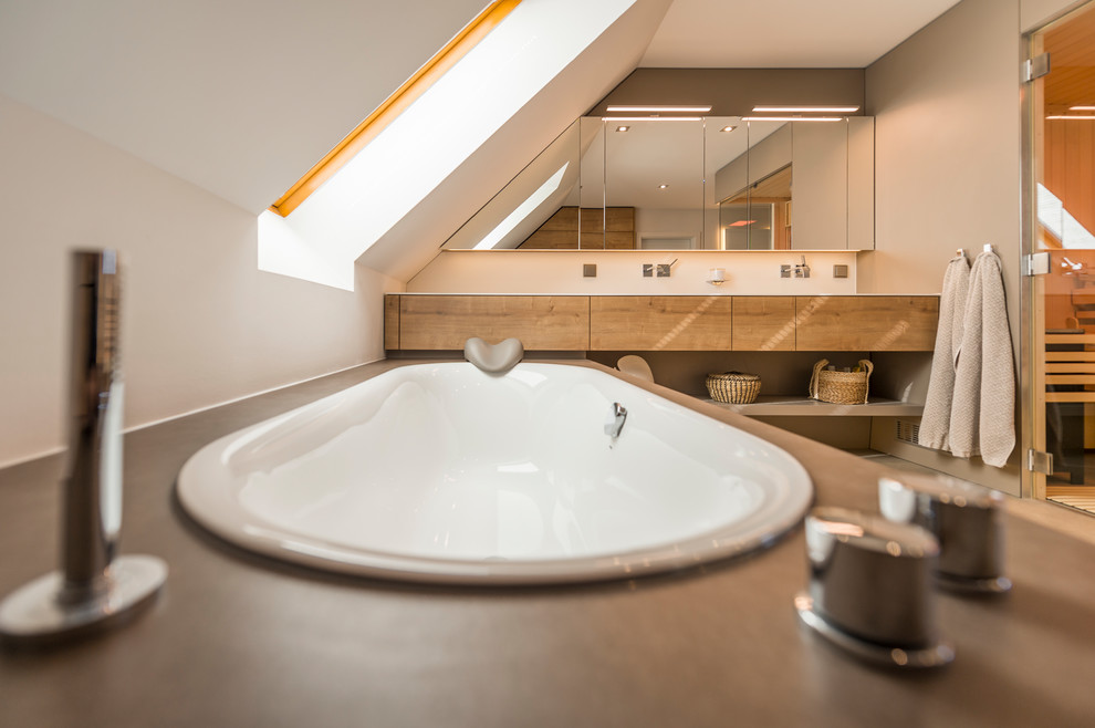 Inspiration for a mid-sized contemporary bathroom in Dresden with a drop-in tub, a curbless shower, a wall-mount toilet, an integrated sink, brown floor and a sliding shower screen.