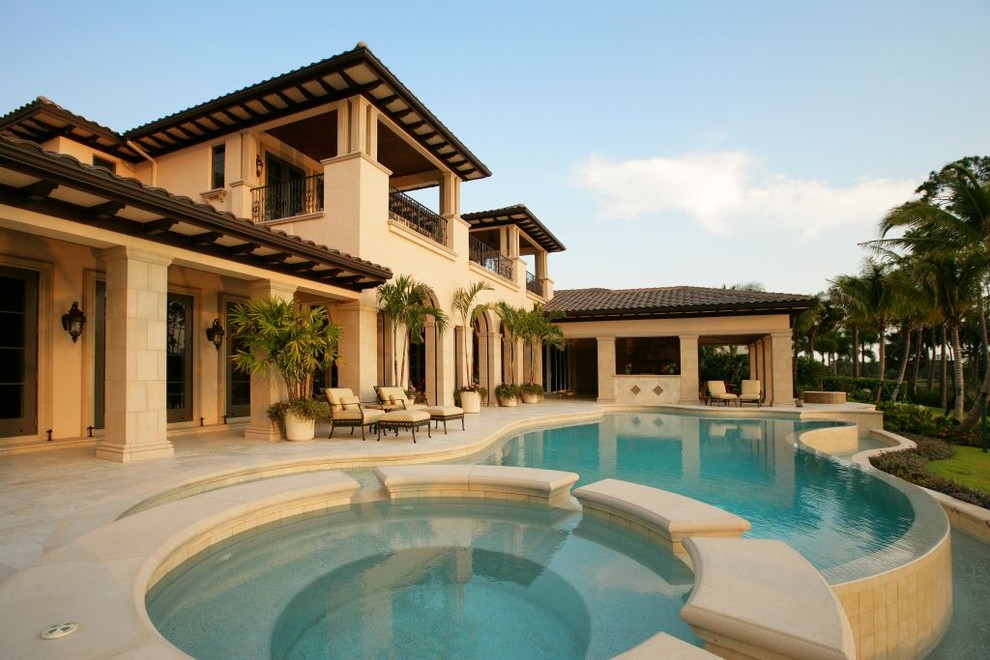 Photo of a mid-sized mediterranean backyard custom-shaped infinity pool in Miami with a hot tub and concrete pavers.