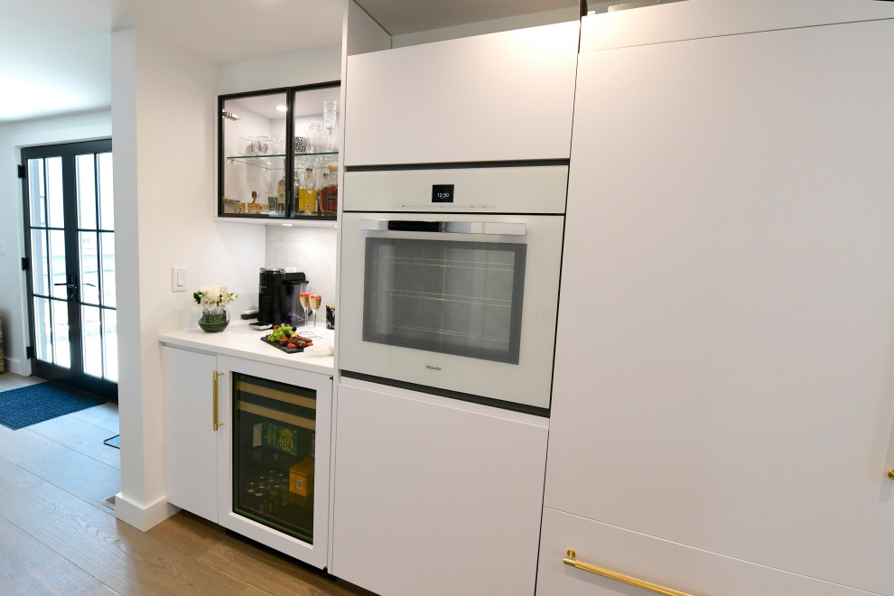 Kitchen - large galley light wood floor, beige floor and coffered ceiling kitchen idea in Boston with a double-bowl sink, flat-panel cabinets, white cabinets, granite countertops, white backsplash, granite backsplash, white appliances, two islands and white countertops