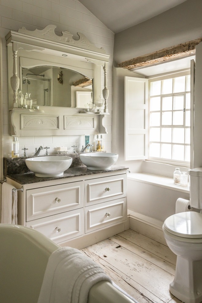 Inspiration for a mid-sized country kids bathroom in Other with shaker cabinets, white cabinets, a claw-foot tub, a two-piece toilet, white tile, ceramic tile, white walls, painted wood floors, a trough sink, marble benchtops and white floor.