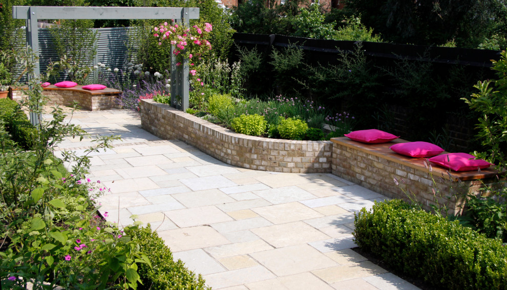 Photo of a small traditional front yard partial sun formal garden for summer in Kent with with raised garden bed and natural stone pavers.