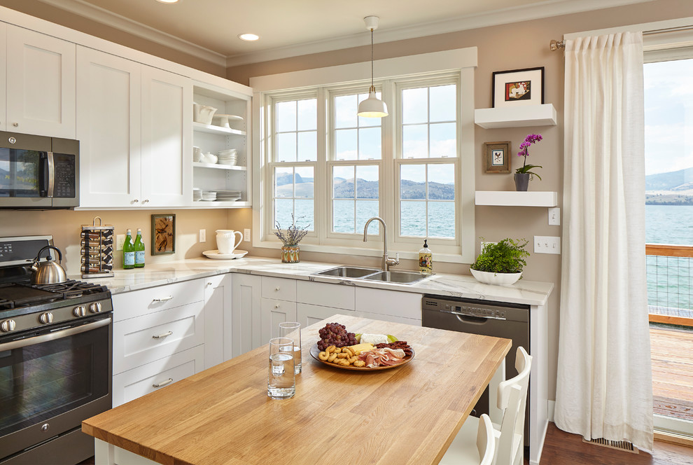 This is an example of a transitional l-shaped kitchen in Other with a double-bowl sink, shaker cabinets, white cabinets, stainless steel appliances, medium hardwood floors, with island, brown floor and white benchtop.