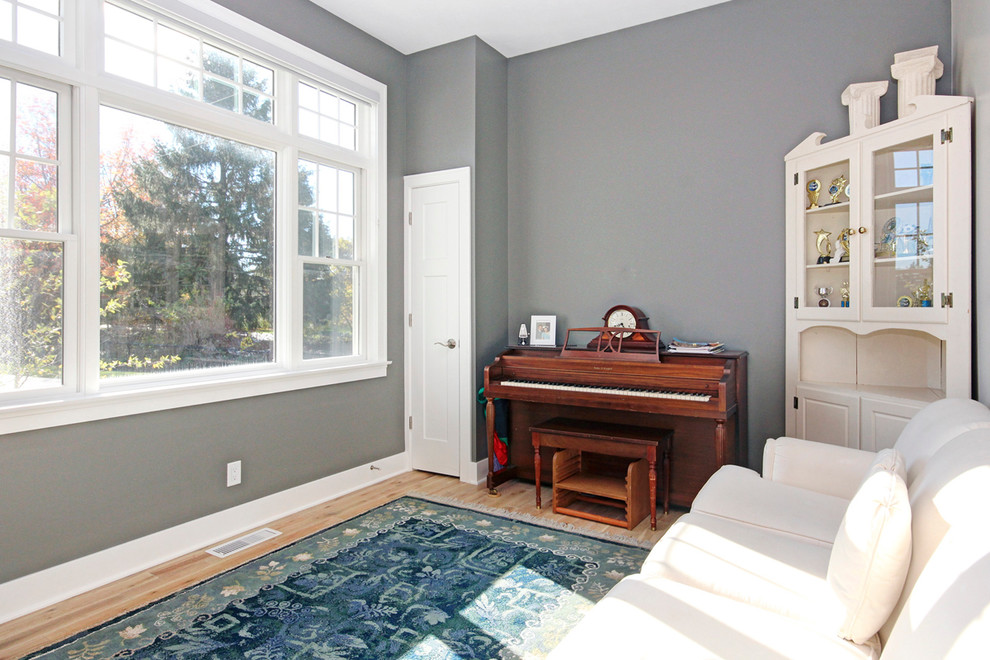 Photo of a beach style bedroom in Grand Rapids with grey walls and light hardwood floors.