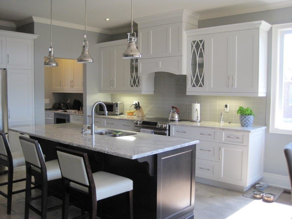 Example of a mid-sized transitional galley travertine floor and beige floor eat-in kitchen design in Toronto with a double-bowl sink, shaker cabinets, white cabinets, marble countertops, gray backsplash, glass tile backsplash, stainless steel appliances and an island