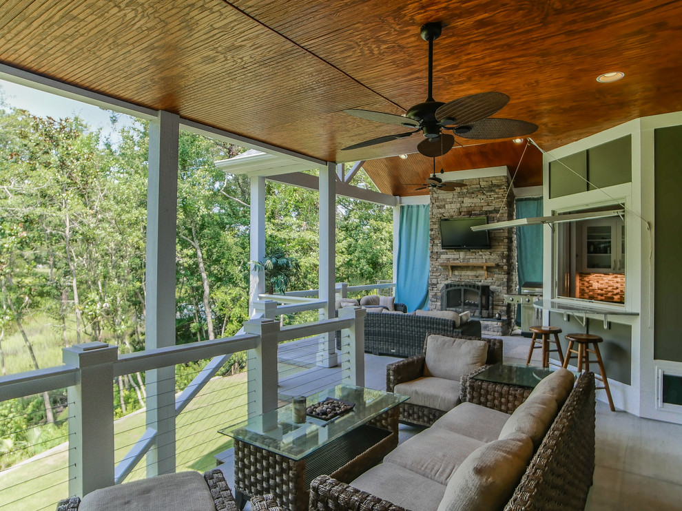 Example of a large transitional backyard deck design with a fire pit and a roof extension