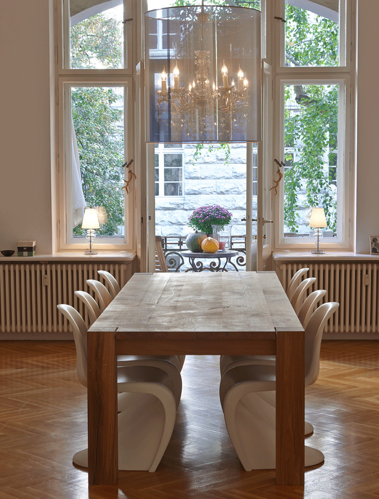 Large contemporary open plan dining in Berlin with light hardwood floors and white walls.