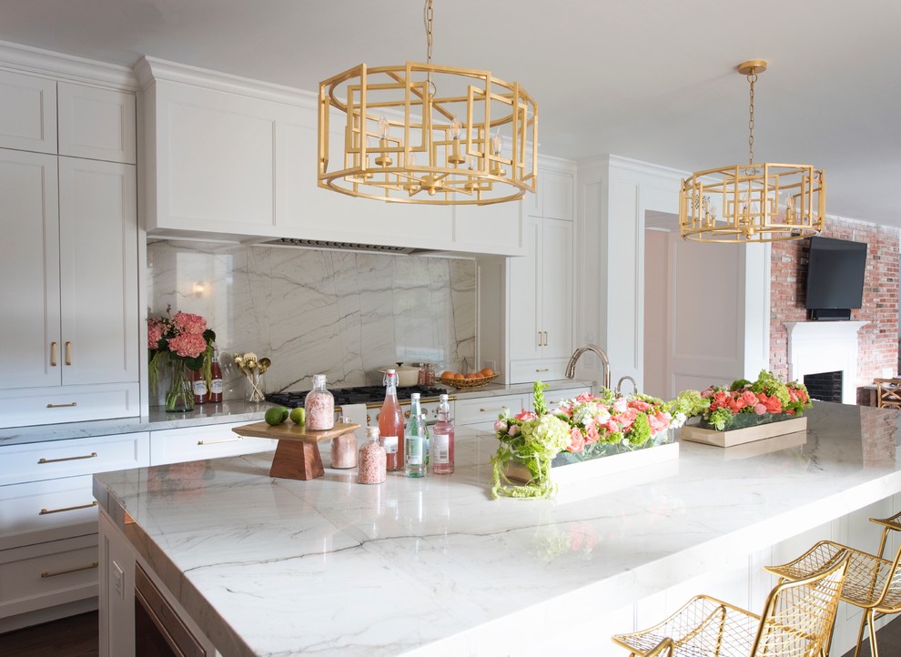 Example of a large transitional l-shaped medium tone wood floor and brown floor open concept kitchen design with a farmhouse sink, recessed-panel cabinets, white cabinets, quartzite countertops, white backsplash, stone slab backsplash, paneled appliances and an island