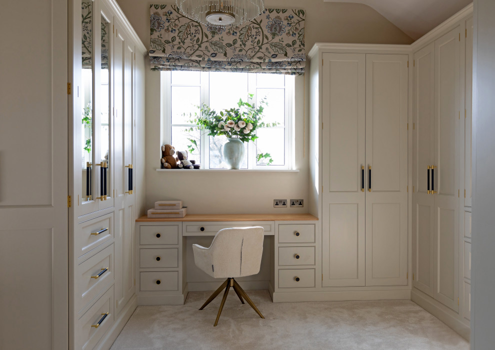 This is an example of a classic dressing room for women in Hampshire with beige cabinets, carpet, beige floors and a vaulted ceiling.