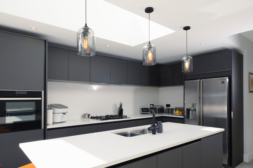 Offene Moderne Küche in L-Form mit schwarzen Schränken, Küchenrückwand in Weiß, Kücheninsel und weißer Arbeitsplatte in London