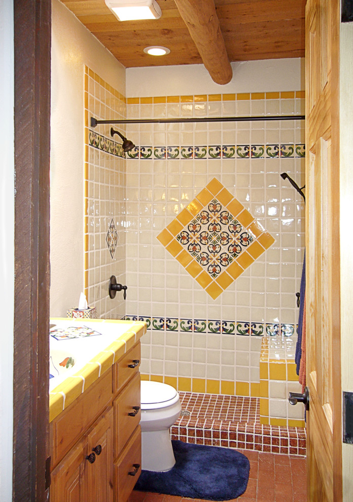 Inspiration for a mid-sized 3/4 bathroom in Portland with raised-panel cabinets, light wood cabinets, an alcove shower, a one-piece toilet, blue tile, white tile, yellow tile, ceramic tile, white walls, brick floors, an integrated sink, tile benchtops, red floor and a shower curtain.