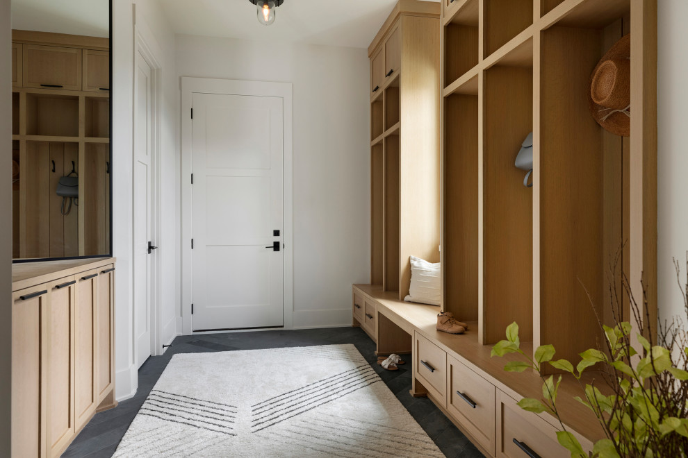 This is an example of a transitional mudroom in Minneapolis with white walls, porcelain floors, a single front door, a white front door and black floor.