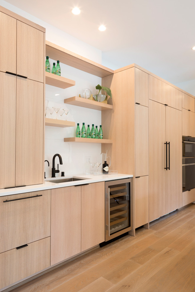 Photo of a contemporary wet bar in Minneapolis with a submerged sink, flat-panel cabinets, light wood cabinets, white splashback, light hardwood flooring and white worktops.