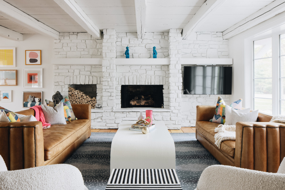 Großes, Offenes Stilmix Wohnzimmer mit weißer Wandfarbe, hellem Holzboden, Kamin, Kaminumrandung aus Stein und freigelegten Dachbalken in Grand Rapids