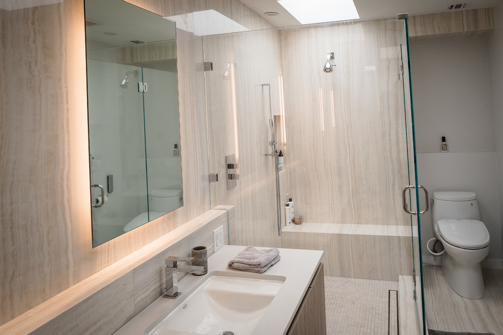 This is an example of a mid-sized modern master bathroom in Los Angeles with flat-panel cabinets, dark wood cabinets, an undermount tub, a curbless shower, a wall-mount toilet, brown tile, marble, brown walls, marble floors, a vessel sink, engineered quartz benchtops, white floor, an open shower and white benchtops.
