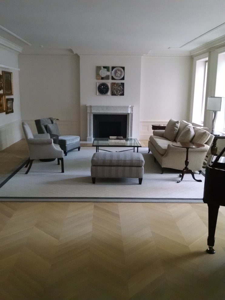This is an example of a large traditional formal enclosed living room in New York with white walls, light hardwood floors, a standard fireplace, a stone fireplace surround, no tv and brown floor.