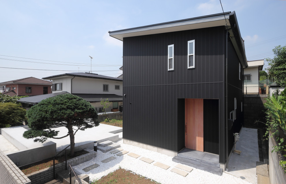 Small modern two-storey black house exterior in Yokohama with metal siding, a shed roof, a metal roof, a grey roof and board and batten siding.