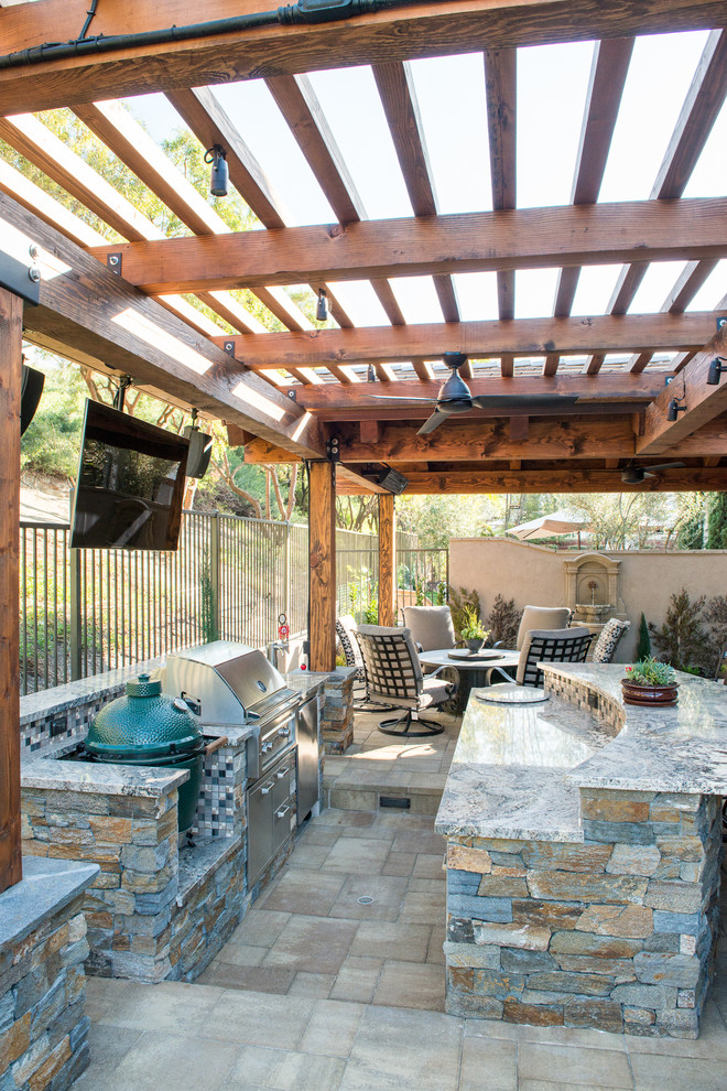 Patio kitchen - mid-sized transitional backyard stone patio kitchen idea in Orange County with a pergola