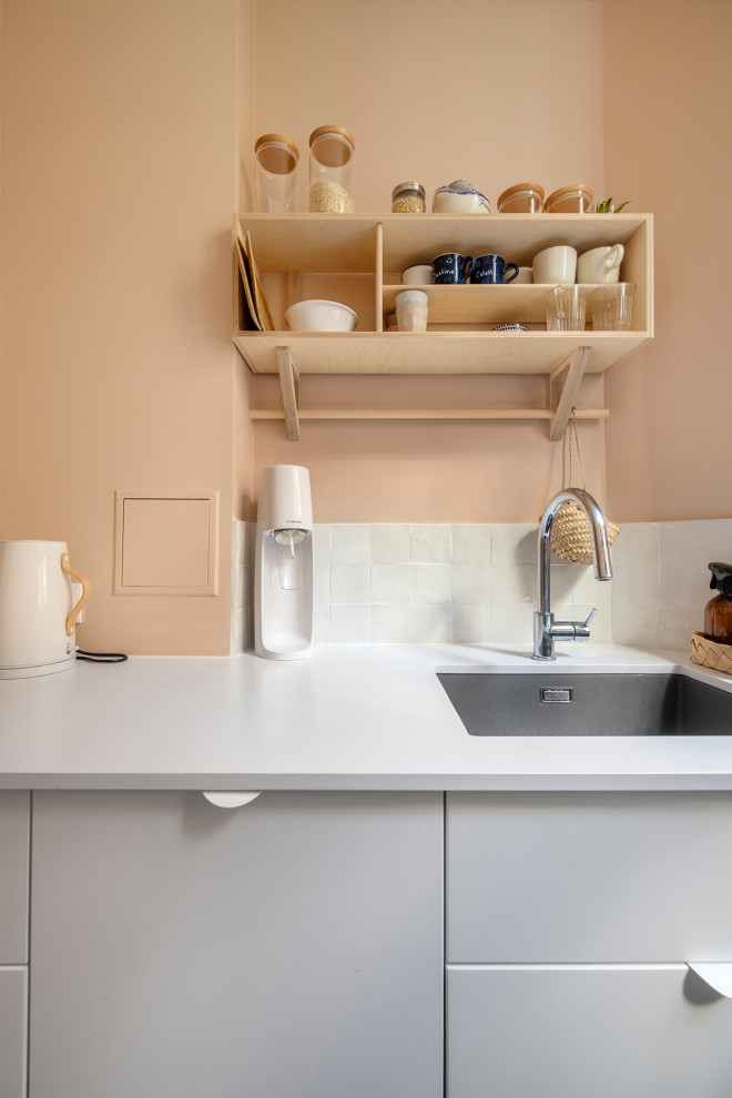 This is an example of a small traditional galley separate kitchen in Paris with an undermount sink, beaded inset cabinets, pink cabinets, quartzite benchtops, white splashback, terra-cotta splashback, panelled appliances, terrazzo floors, no island, white floor and pink benchtop.
