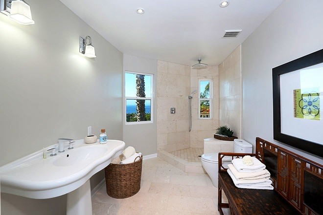 Photo of a mid-sized beach style 3/4 bathroom in Orange County with raised-panel cabinets, beige cabinets, a corner tub, an open shower, a one-piece toilet, ceramic tile, grey walls, ceramic floors, a trough sink, solid surface benchtops, beige floor and an open shower.