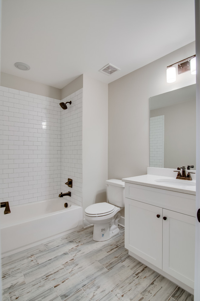 Mid-sized traditional bathroom in Nashville with white cabinets, a shower/bathtub combo, white tile, beige walls, porcelain floors and quartzite benchtops.