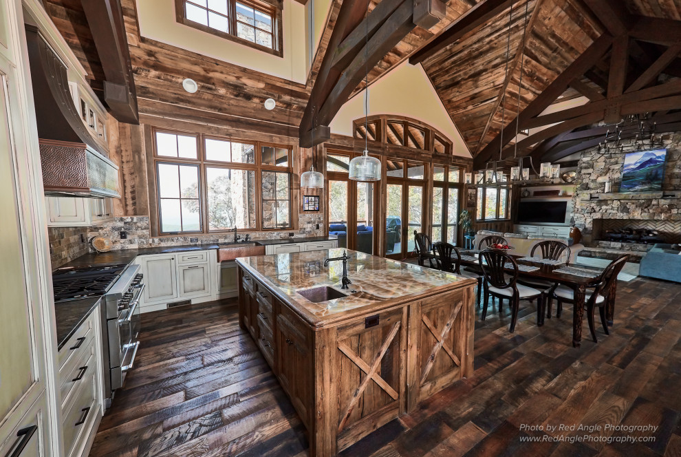 Inspiration for a large rustic dark wood floor and exposed beam kitchen remodel with a farmhouse sink, shaker cabinets, distressed cabinets, granite countertops, stone tile backsplash, stainless steel appliances and an island