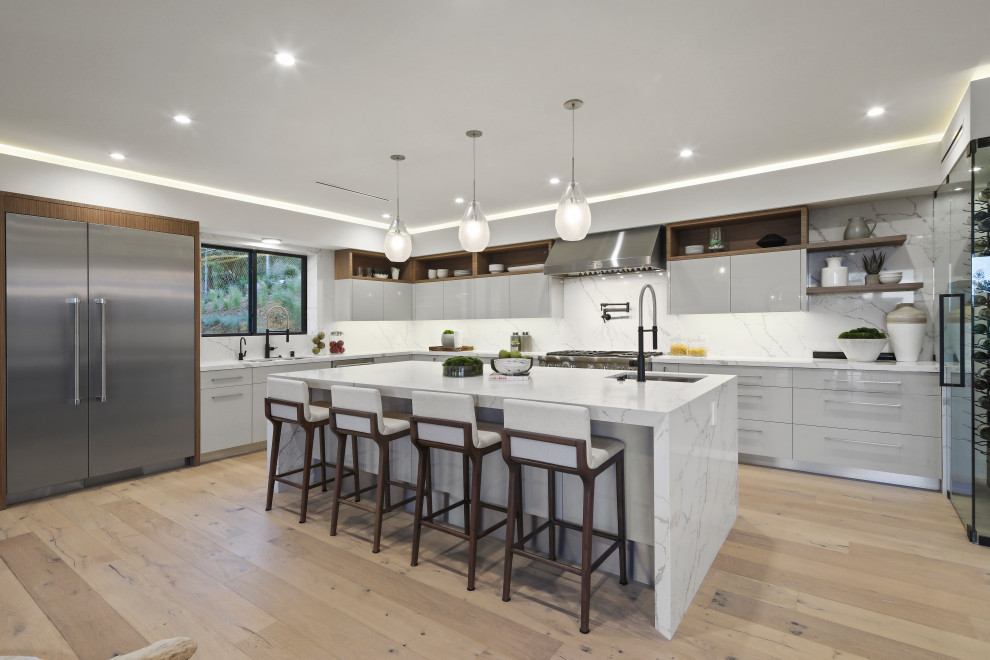 Design ideas for an expansive contemporary u-shaped kitchen in Los Angeles with an undermount sink, flat-panel cabinets, grey cabinets, white splashback, stainless steel appliances, light hardwood floors, with island, beige floor and white benchtop.