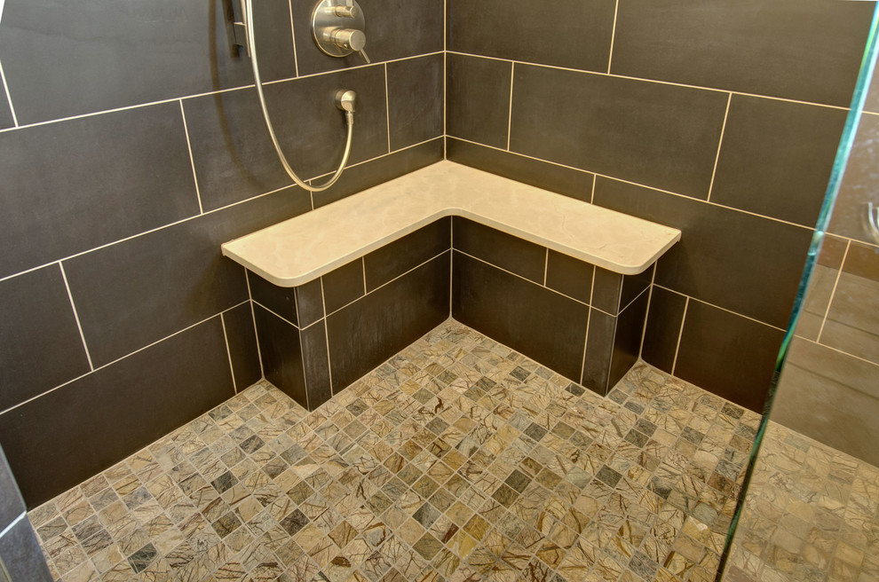 This is an example of a mid-sized transitional bathroom in Denver with flat-panel cabinets, light wood cabinets, a corner shower, a two-piece toilet, black tile, slate, grey walls, terra-cotta floors, an undermount sink, tile benchtops, brown floor, a hinged shower door and grey benchtops.