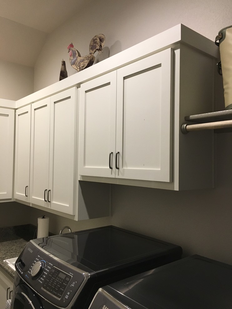 Inspiration for a small traditional l-shaped laundry room in Austin with a drop-in sink, recessed-panel cabinets, white cabinets, granite benchtops, grey walls, concrete floors, a side-by-side washer and dryer and grey floor.