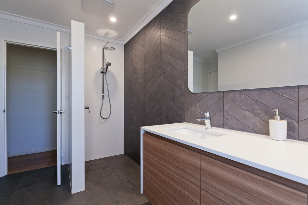 Inspiration for a mid-sized contemporary master bathroom in Perth with flat-panel cabinets, medium wood cabinets, an open shower, a two-piece toilet, gray tile, porcelain tile, white walls, porcelain floors, an undermount sink, engineered quartz benchtops, grey floor, an open shower and white benchtops.