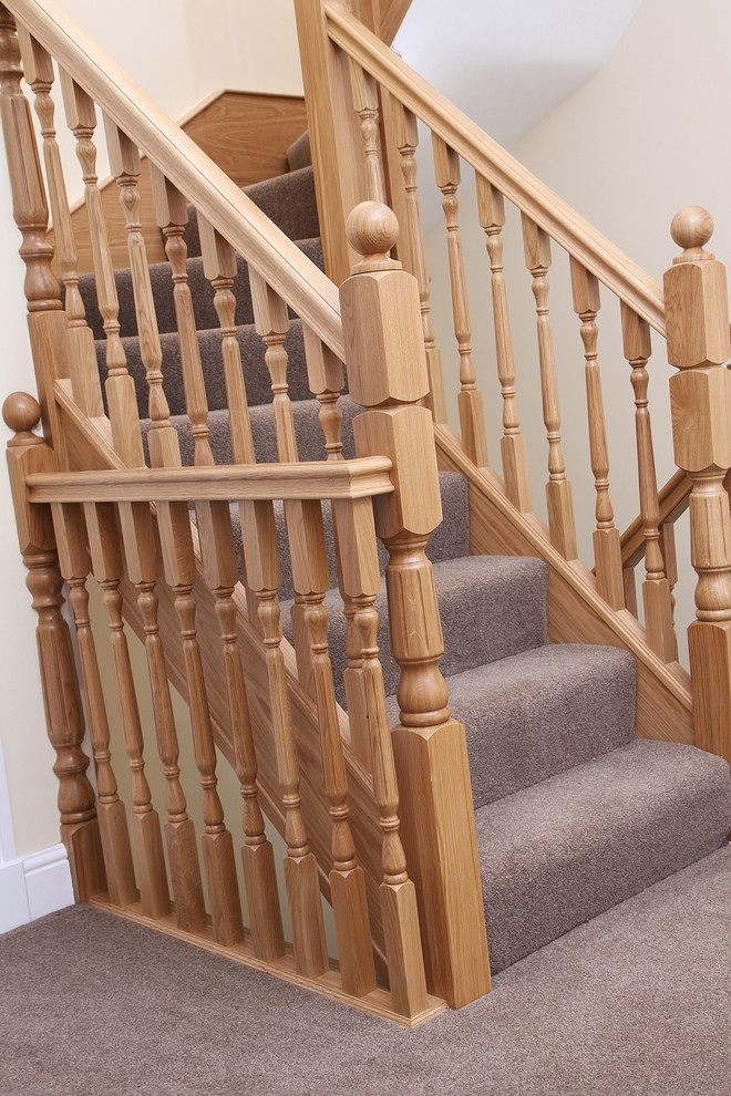 This is an example of a traditional carpeted u-shaped staircase in Cheshire with carpet risers and wood railing.