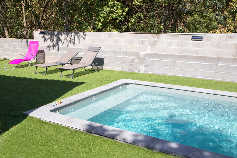 Photo of a mid-sized contemporary rectangular pool in Toulouse with a pool house and concrete slab.
