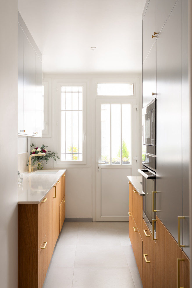 Design ideas for a mid-sized modern galley separate kitchen in Paris with an integrated sink, beaded inset cabinets, light wood cabinets, quartzite benchtops, white splashback, engineered quartz splashback, panelled appliances, concrete floors, no island, grey floor and white benchtop.