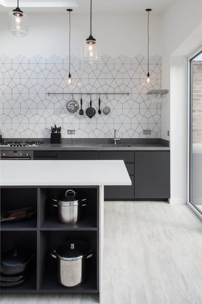 Contemporary kitchen in London with an undermount sink, flat-panel cabinets, black cabinets, white splashback and with island.