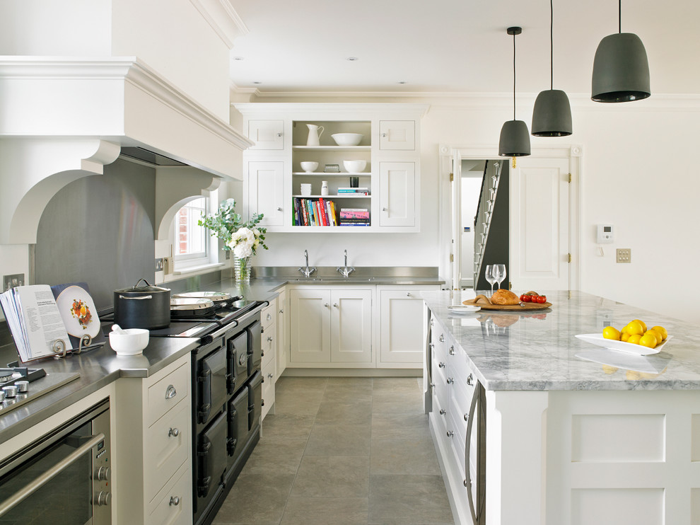 Inspiration for a transitional l-shaped kitchen in London with shaker cabinets, white cabinets, stainless steel benchtops, metallic splashback, black appliances and with island.
