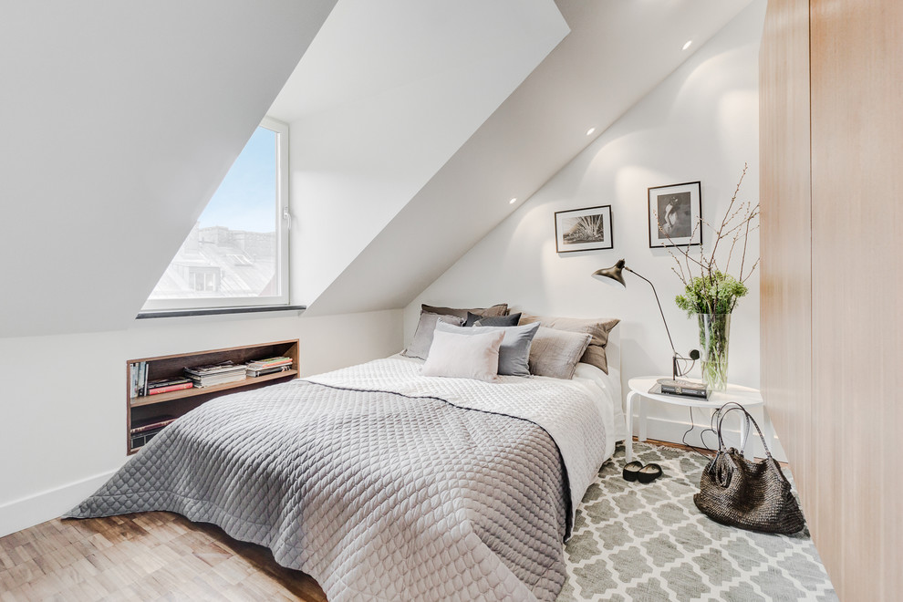 This is an example of a mid-sized scandinavian master bedroom in Stockholm with white walls, light hardwood floors, no fireplace and brown floor.