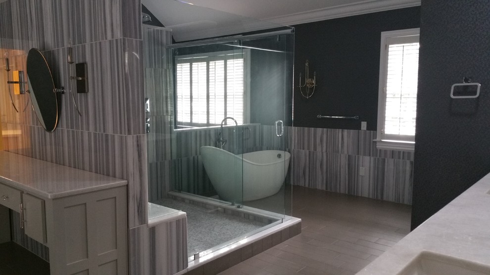 Large transitional master gray tile and porcelain tile light wood floor and beige floor freestanding bathtub photo with white cabinets, gray walls, an undermount sink, quartz countertops, a hinged shower door and white countertops