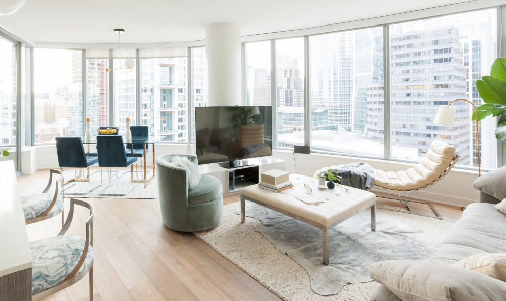 This is an example of a contemporary living room in San Francisco with white walls, light hardwood floors, a freestanding tv and beige floor.