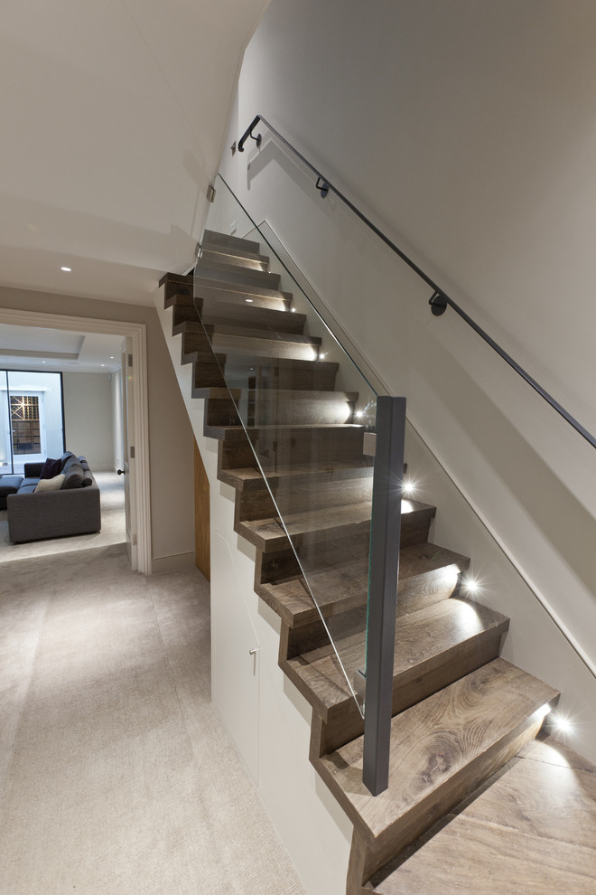 Mid-sized contemporary wood straight staircase in London with wood risers and glass railing.